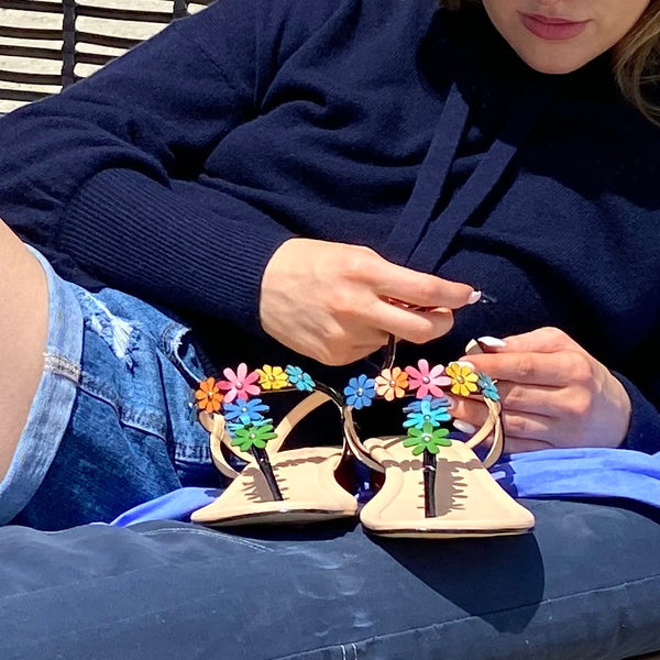 Woman holding Thong Sandal in Black Patent Leather  with Rainbow Colored Flower strap and Blue heel cover
